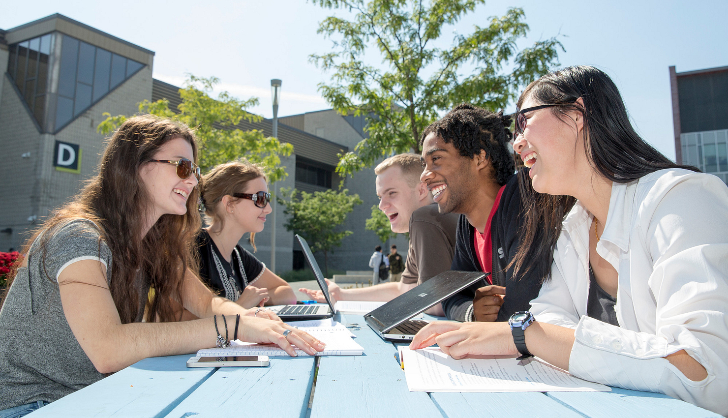 Students sitting at table outdoors in Progress campus courtyard