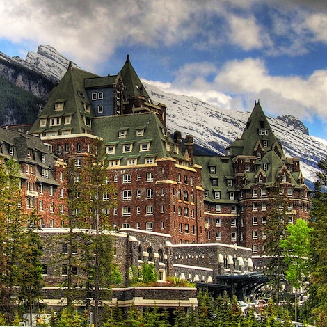 The Banff Springs Hotel is a large, castle like hotel with red walls and green, pointy roofs.