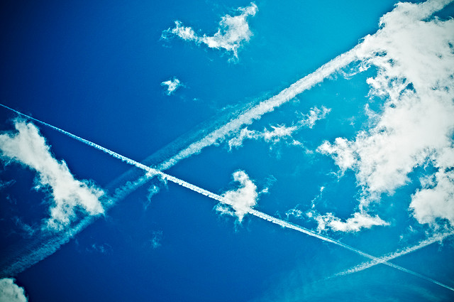 The contrail from a plane streaks across a blue sky.