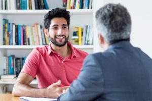 Job interview of brazilian male apprentice with businessman at office