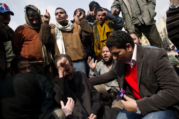 A group of men standing around each other possibly singing or praying.