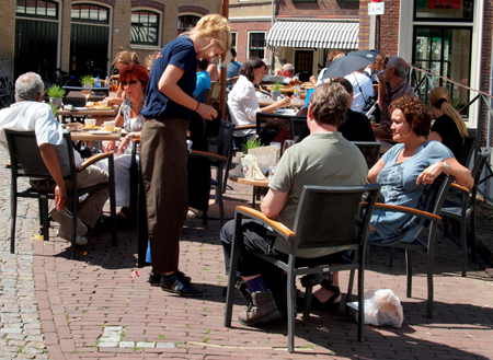 Street cafe scene with a woman taking a couple's order.