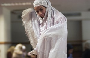 A young girl wears white clothing that only shows her face. She smiles at the camera.