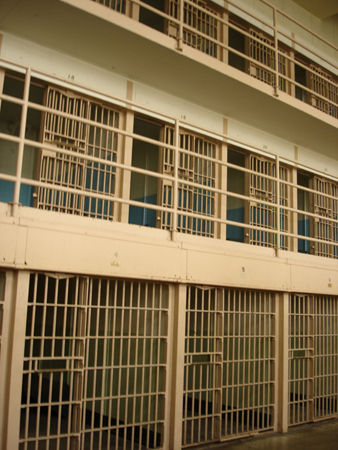 Individual prison cells with sliding bar doors.