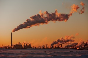 A large plant with tall smokestacks and smoke rising up into the sky.