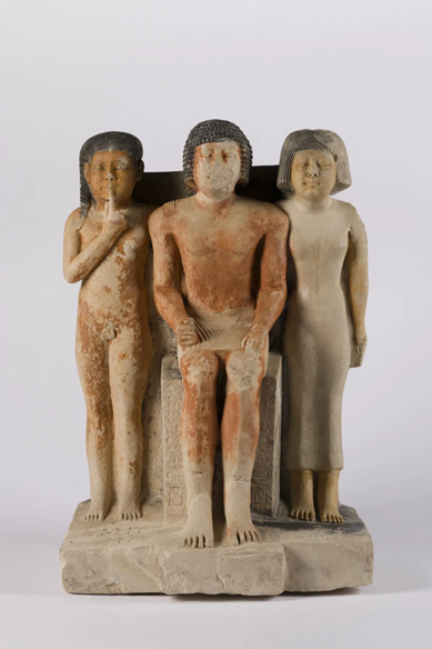A statue of a man seated in the center with his wife and son standing on either side of him