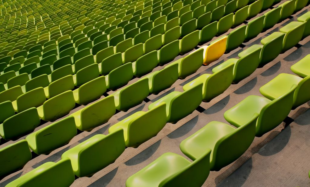 A large number of green chairs with one yellow one