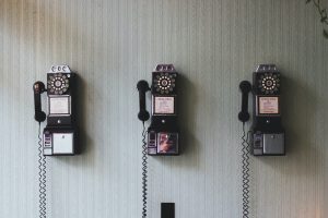 Photo of three large rotary phones on a wall.