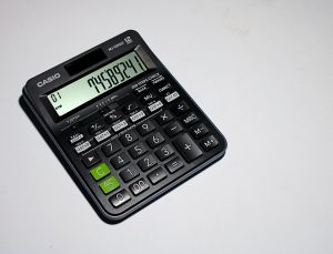 A black calculator on a white desk.