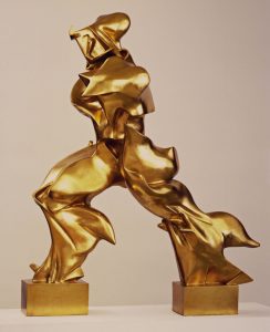A scupture of a figure taking a step. Made of shiny gold the components are irregularly shaped to show the movement.