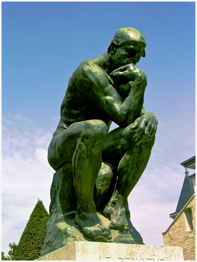 A green stone man seated with a hand under his chin
