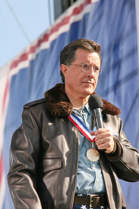 Middle-aged man wearing a leather jacket and a medal, holds a microphone
