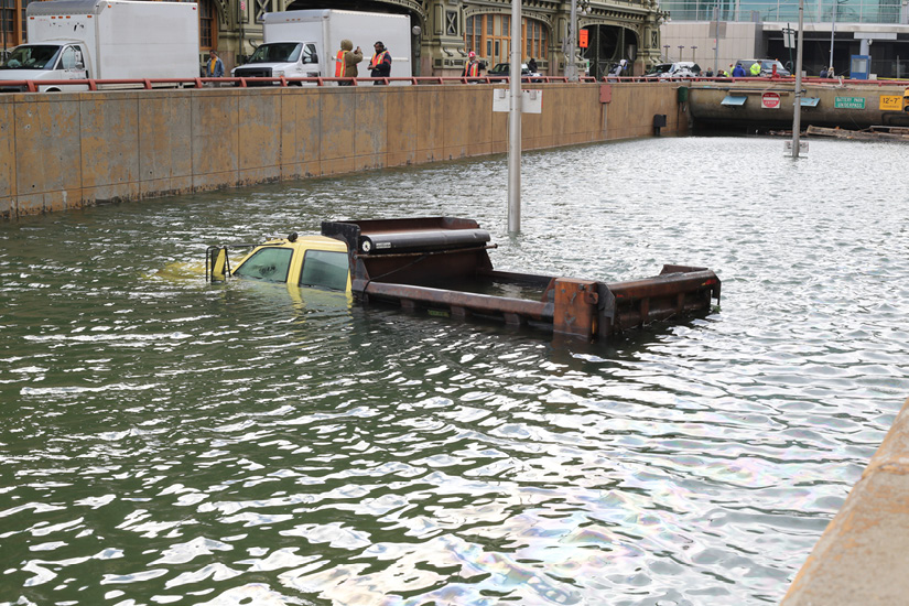 Yellow truck covered by water on a flooded street leading to a tunnel