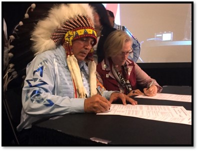 Chief and government official signing a document.