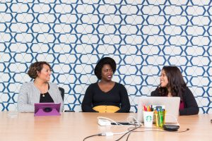 three women stitting at a boardroom table one one side having a discussion