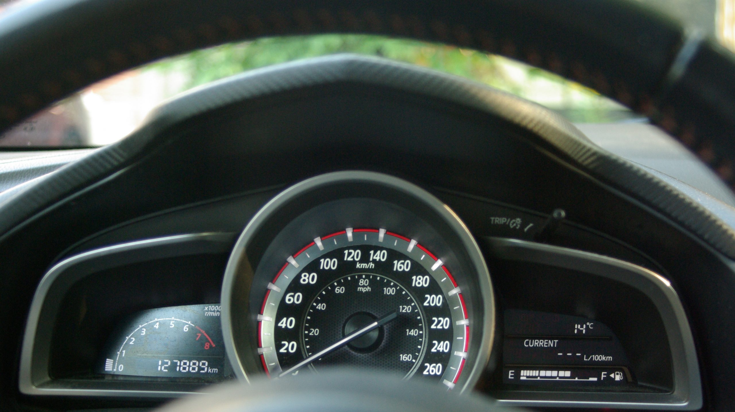 Car dashboard showing speedometer in both kilometers and miles.