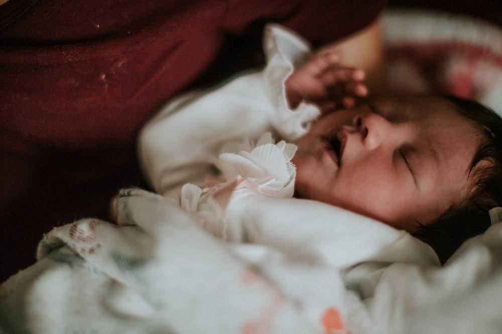 close up image of a newborn baby dressed in white clothing