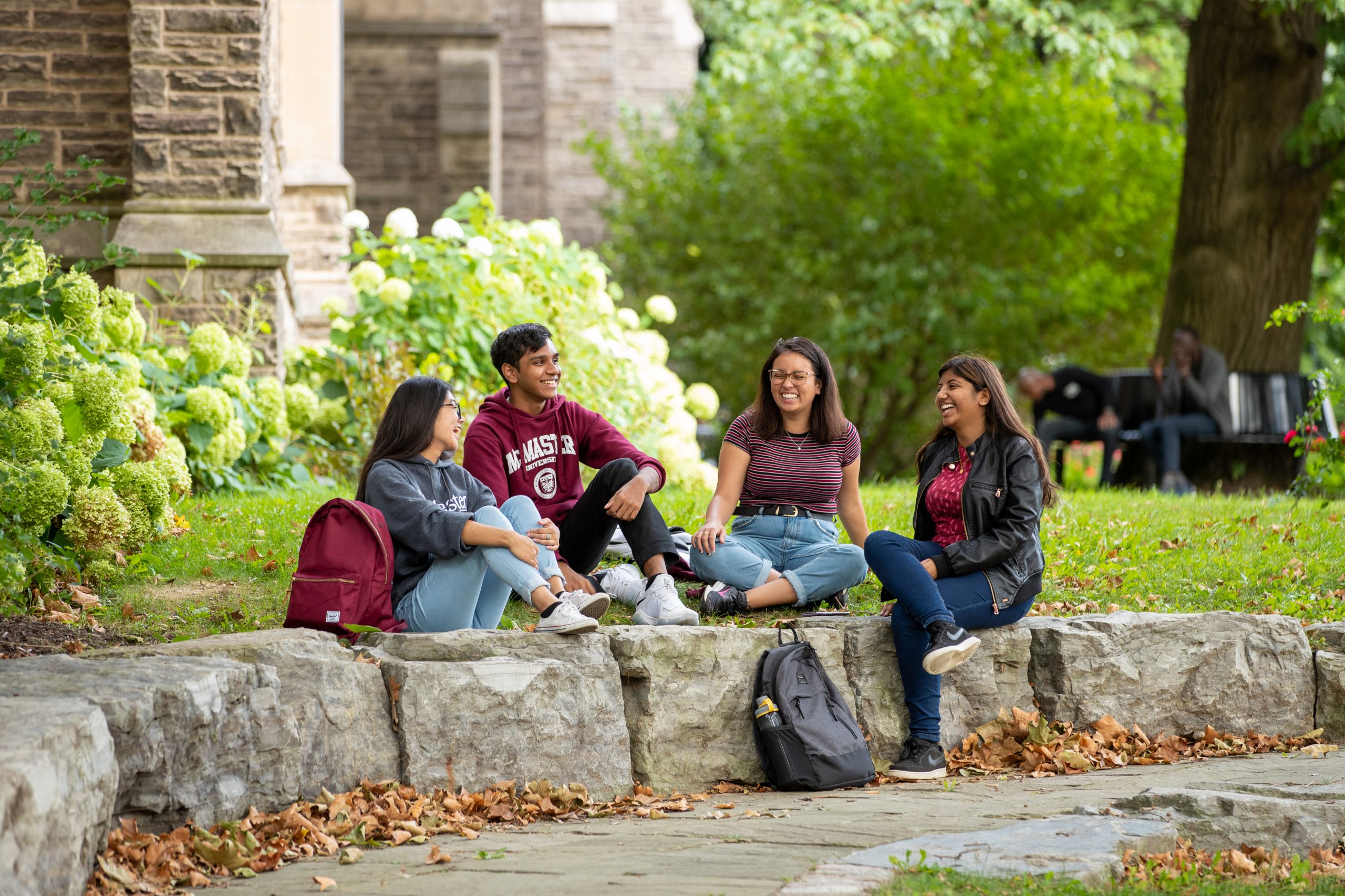 Students from McMaster's international student community sit and talk on campus grounds.