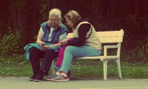 Des femmes âgées discutent, assises sur un banc dans un parc.