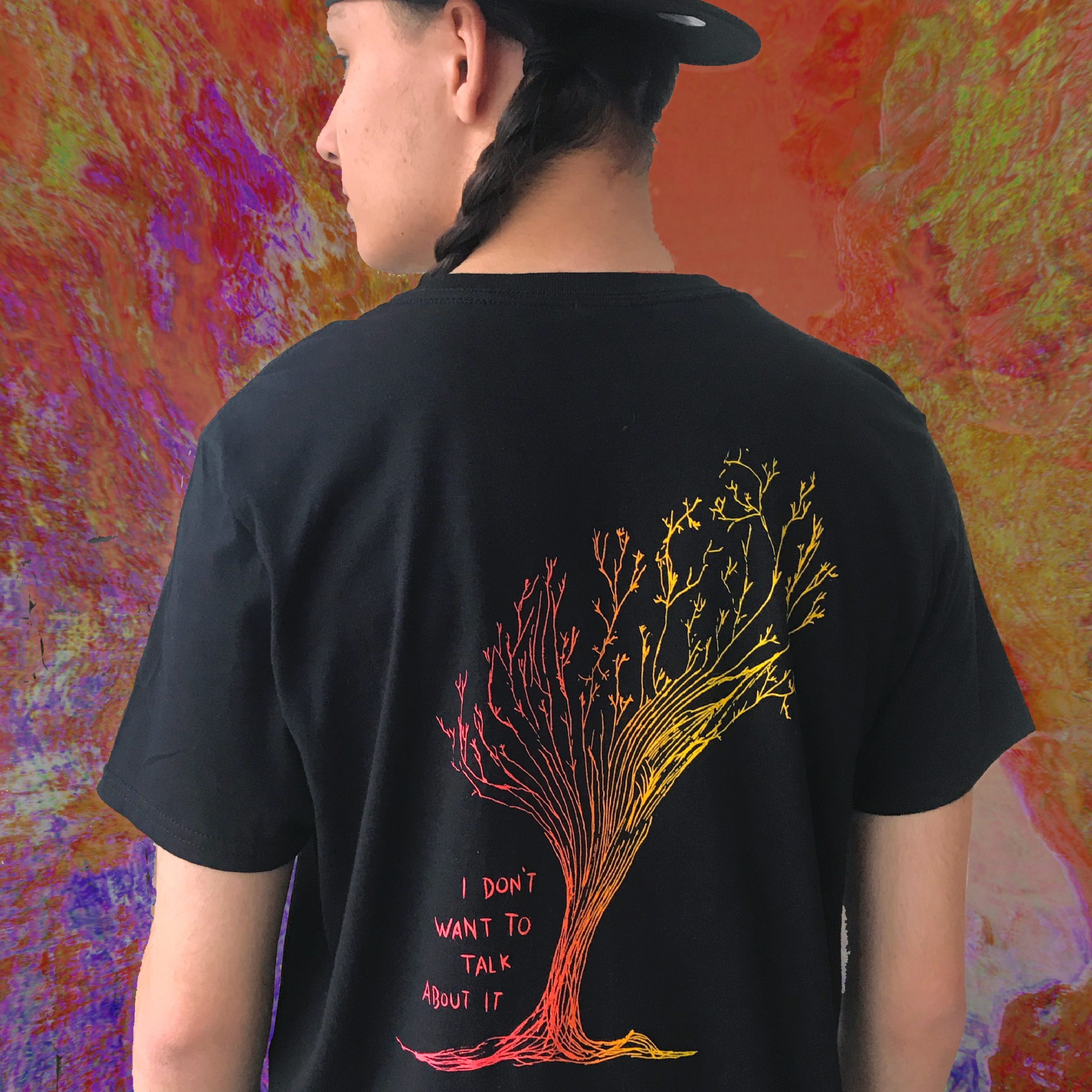 Person with back to the camera, wearing a black T-shirt with a colourful tree design and text "I DON'T WANT TO TALK ABOUT IT" on the back.