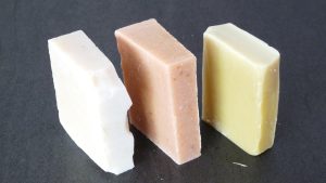 3 bars of soap. From left to right, a white bar of soap, a beige bar of soap and a yellow bar of soap.