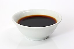 a white cup with soy sauce within it