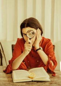 a person holds a magnifying glass to their eye