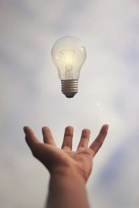 a hand appears under a hovering lightbulb, as if to catch it
