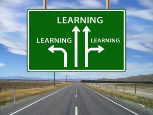 Sign with arrows pointing in different directions and the word learning on it three times.