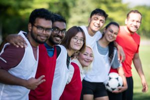 Seven people with soccer ball looking at camera smiling.