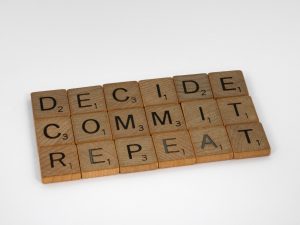 Wooden Scrabble Pieces Spelling out "Decide Commit Repeat"