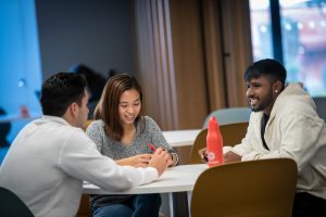 Three students sitting at table smiling