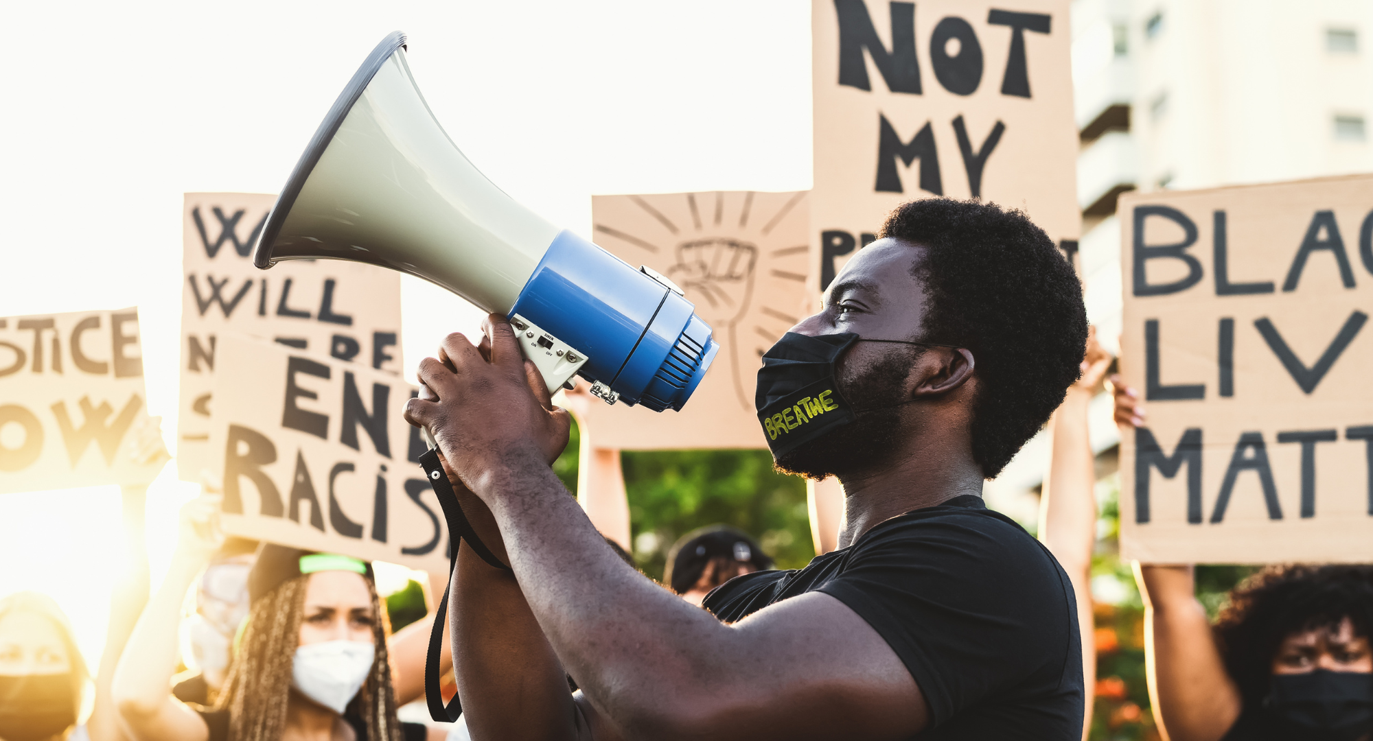 Photo of a young man holding a megaphone during a rally for racial justice.