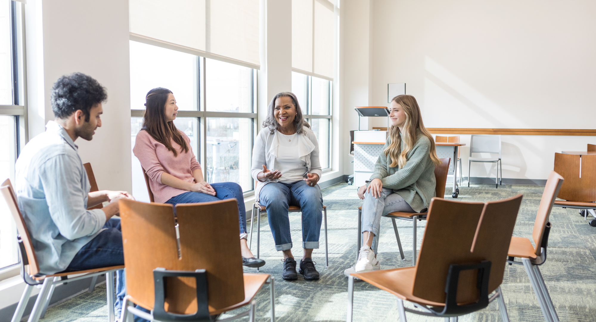 Photo of an university instructor and three students sitting in a circle and having a conversation.