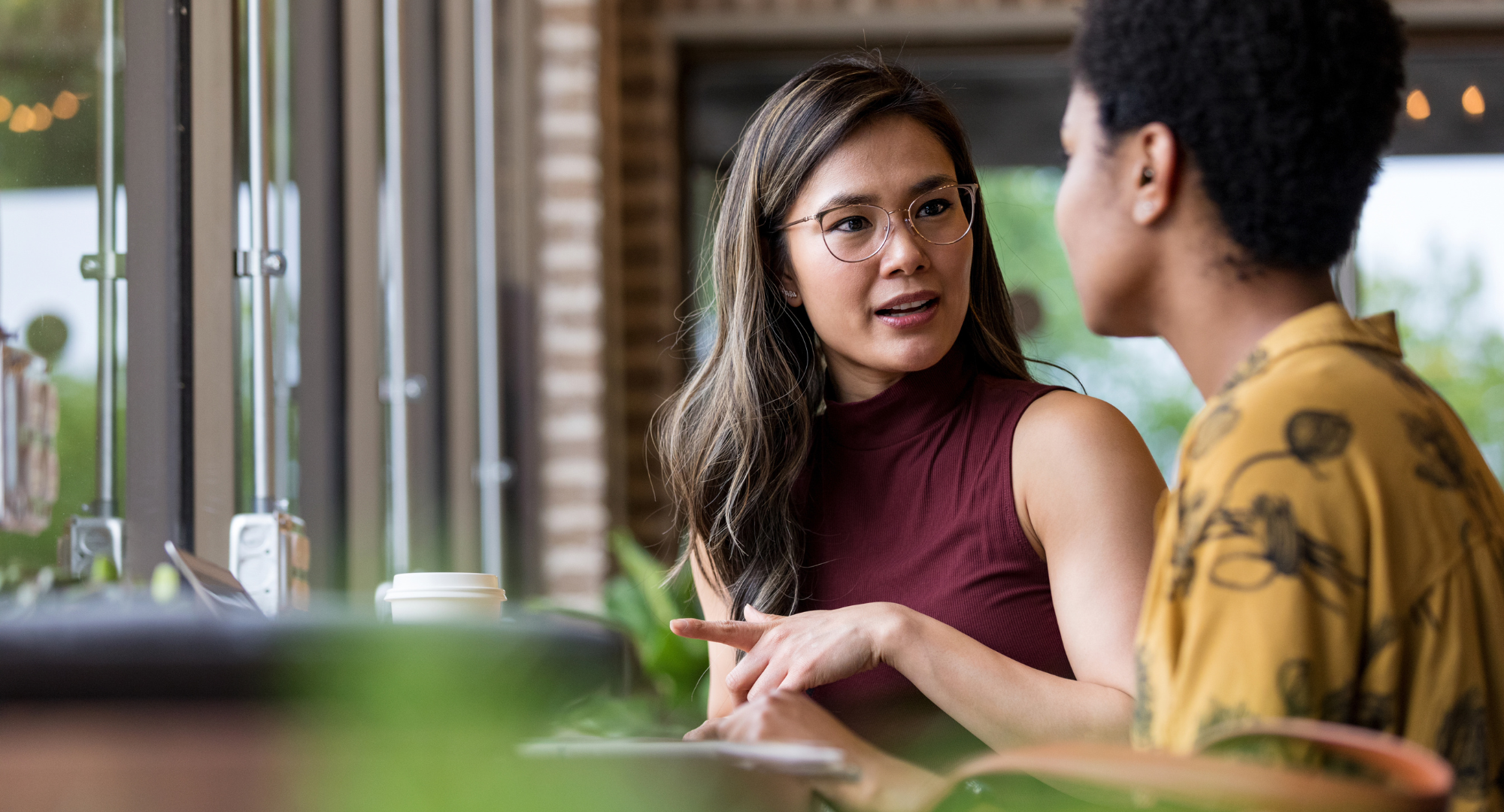 Two people drinking coffee and having a conversation at a table.