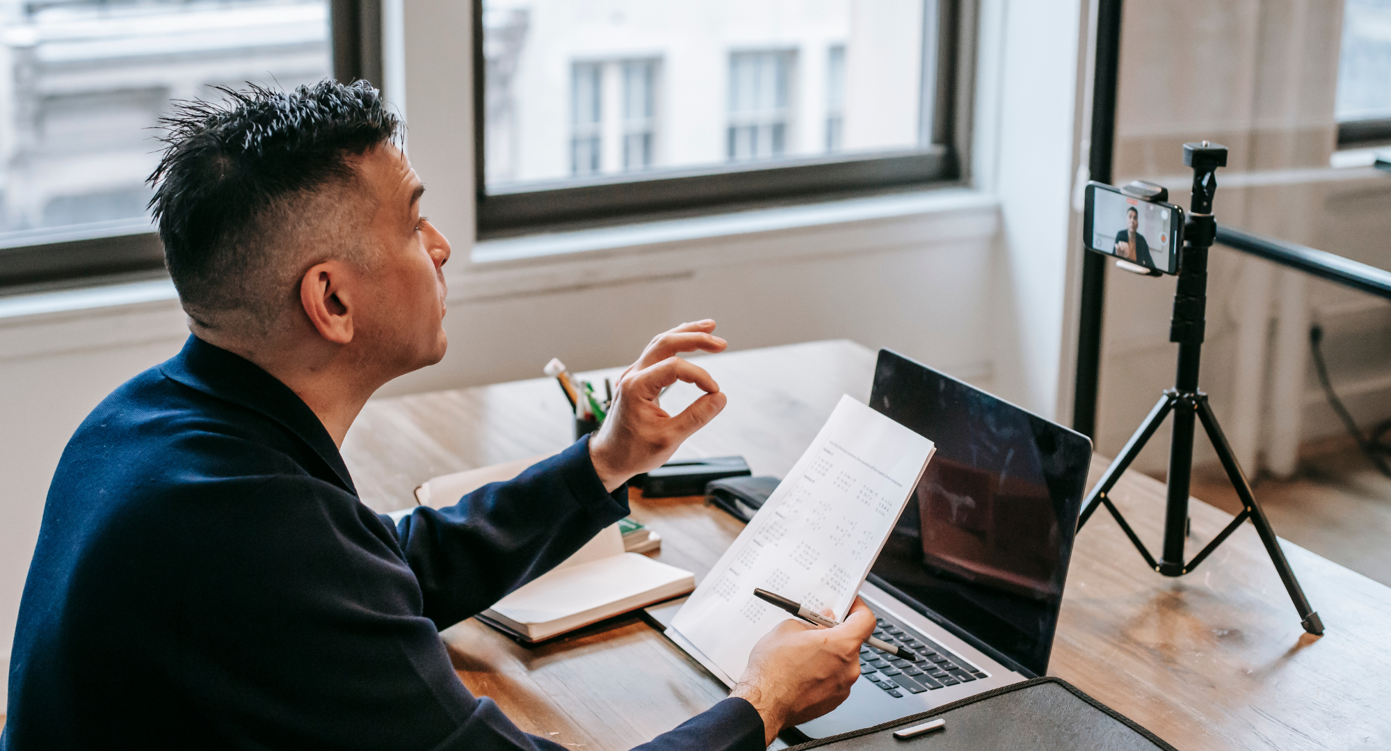 Photo of an instructor teaching online in front of a computer, camera and tripod.