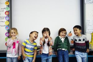 5 Young children making faces in a classroom.