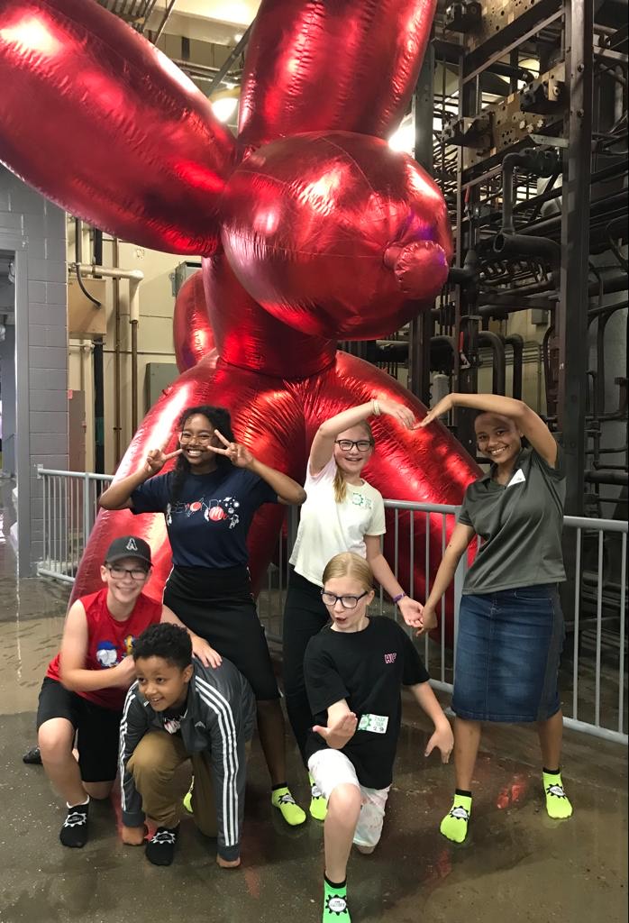 children posing in front of an art installation of a balloon dog