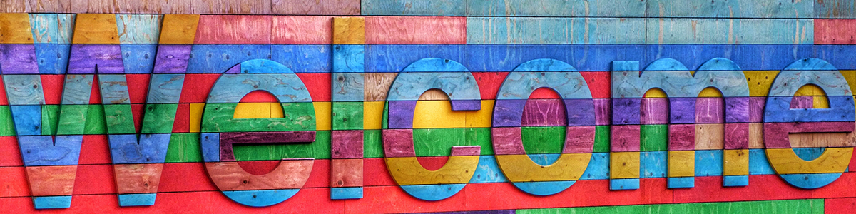 Colorful "Welcome" text atop painted wooden texture wall