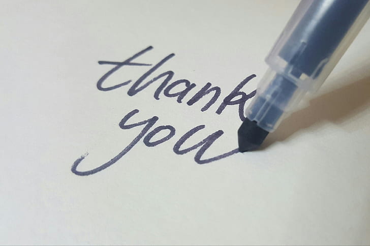 The words "Thank You" being written with a pen.