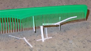 A photograph of thin strips of paper stuck to a plastic comb.