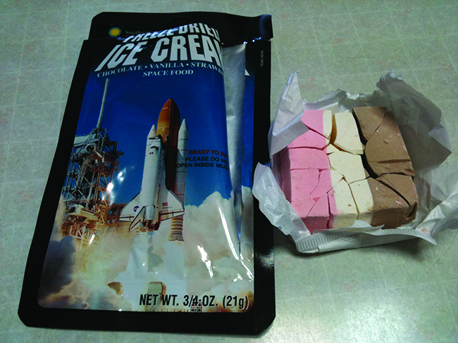 A photograph shows an open package of freeze-dried ice cream and the pink, brown and white stripped freeze-dried ice cream.