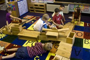 preschool children building a block enclosure on the classroom floor