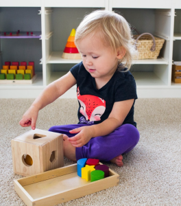 young child playing with a montessori shape sorter