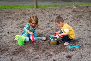 two children playing with sand buckets and rakes