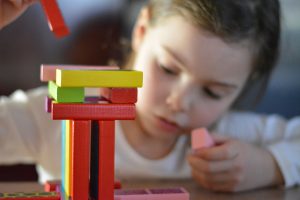 young child stacking colourful block