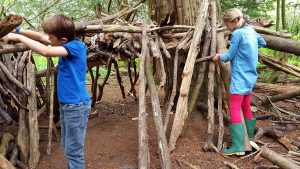 two children playing outdoors and building a fort in the trees