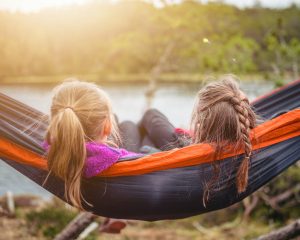 two children laying in a hammock overlooking the water