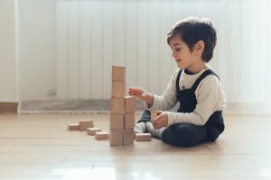 child stacking blocks while sitting on the floor