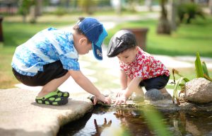 two young chldren playing in a small pond